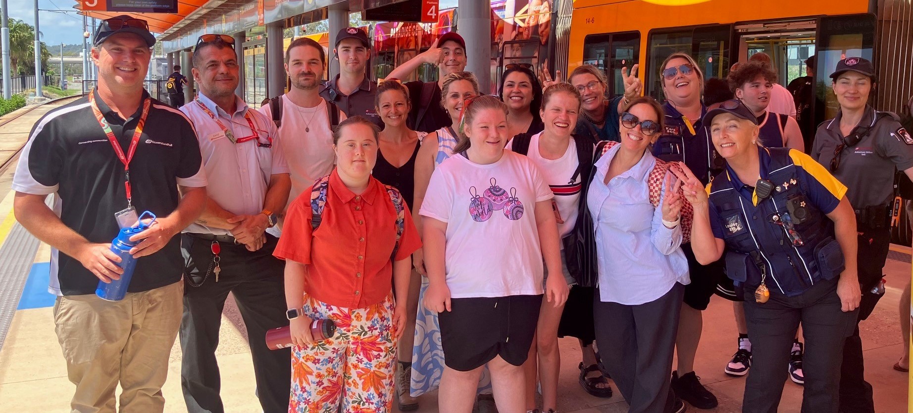 A group of students standing on a train platform with Queensland Rail staff and security teams