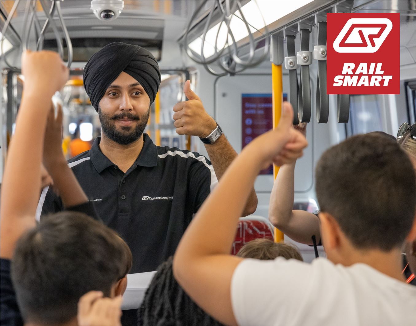 A group of students standing on a train platform with Queensland Rail staff and security teams